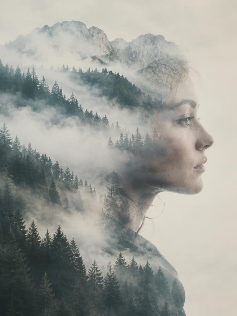 Double exposure portrait of a woman's profile merged with a misty pine forest and mountains